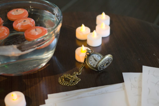 pocketwatch on table with electric candles and candles in bowl of water