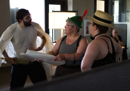 person holding rolled map discussing with two others