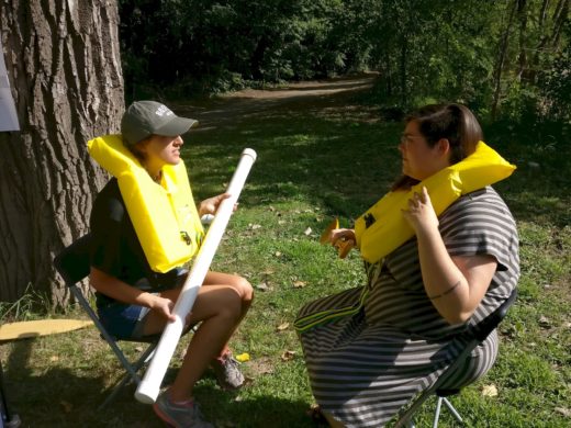 two people in lifevests, simulating rowing